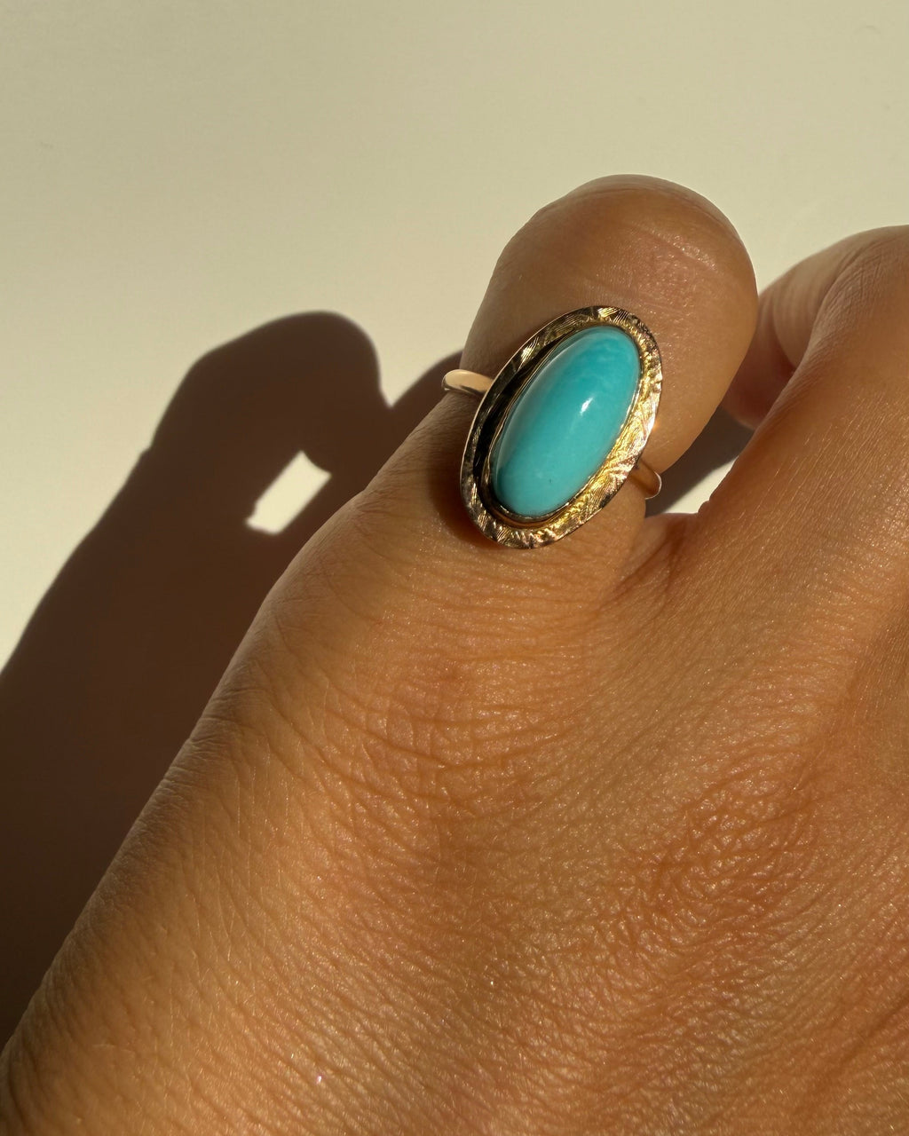 Turquoise ring on a finger with a neutral background